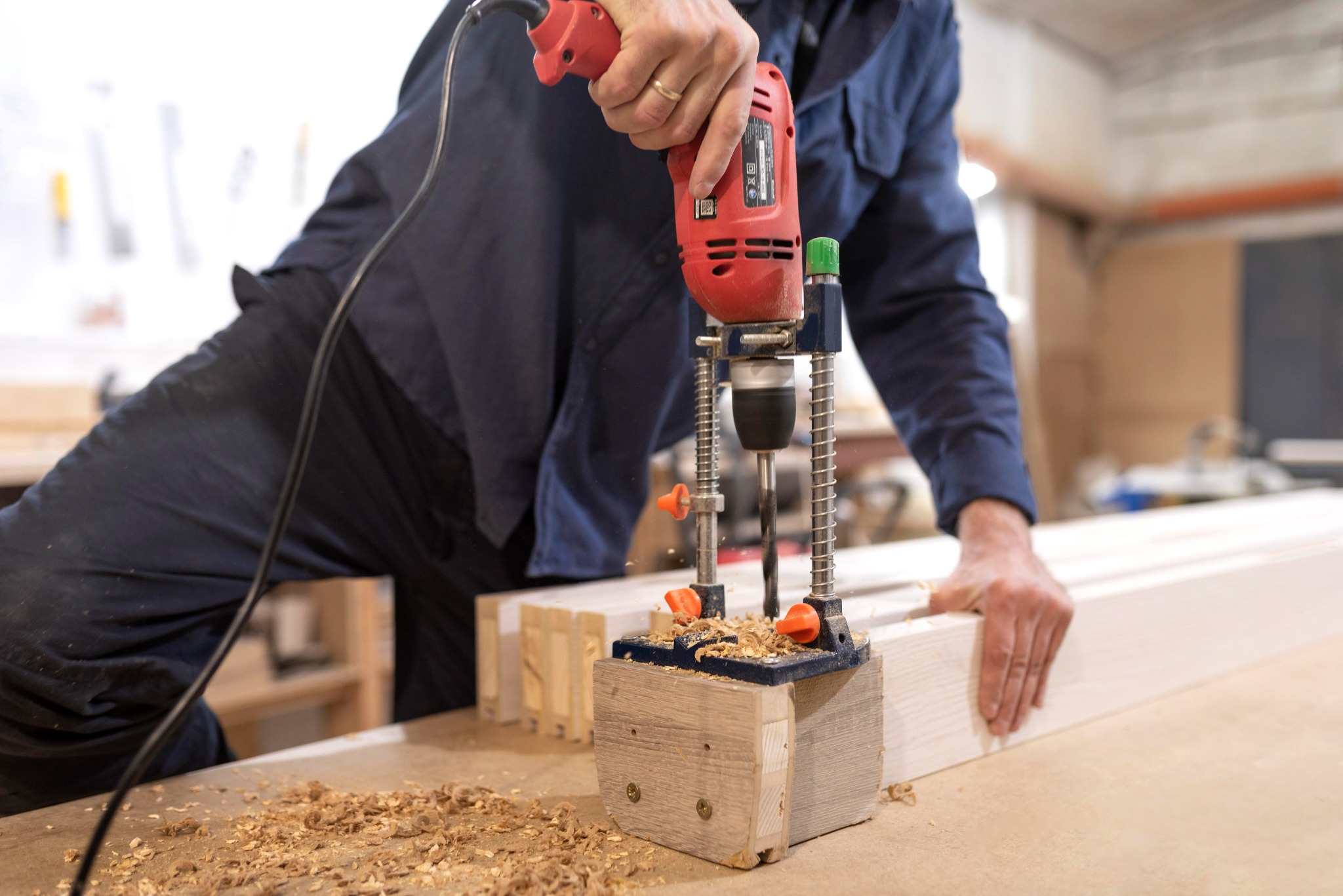 Woodworker using a drill press to create a precise custom timber solution.
