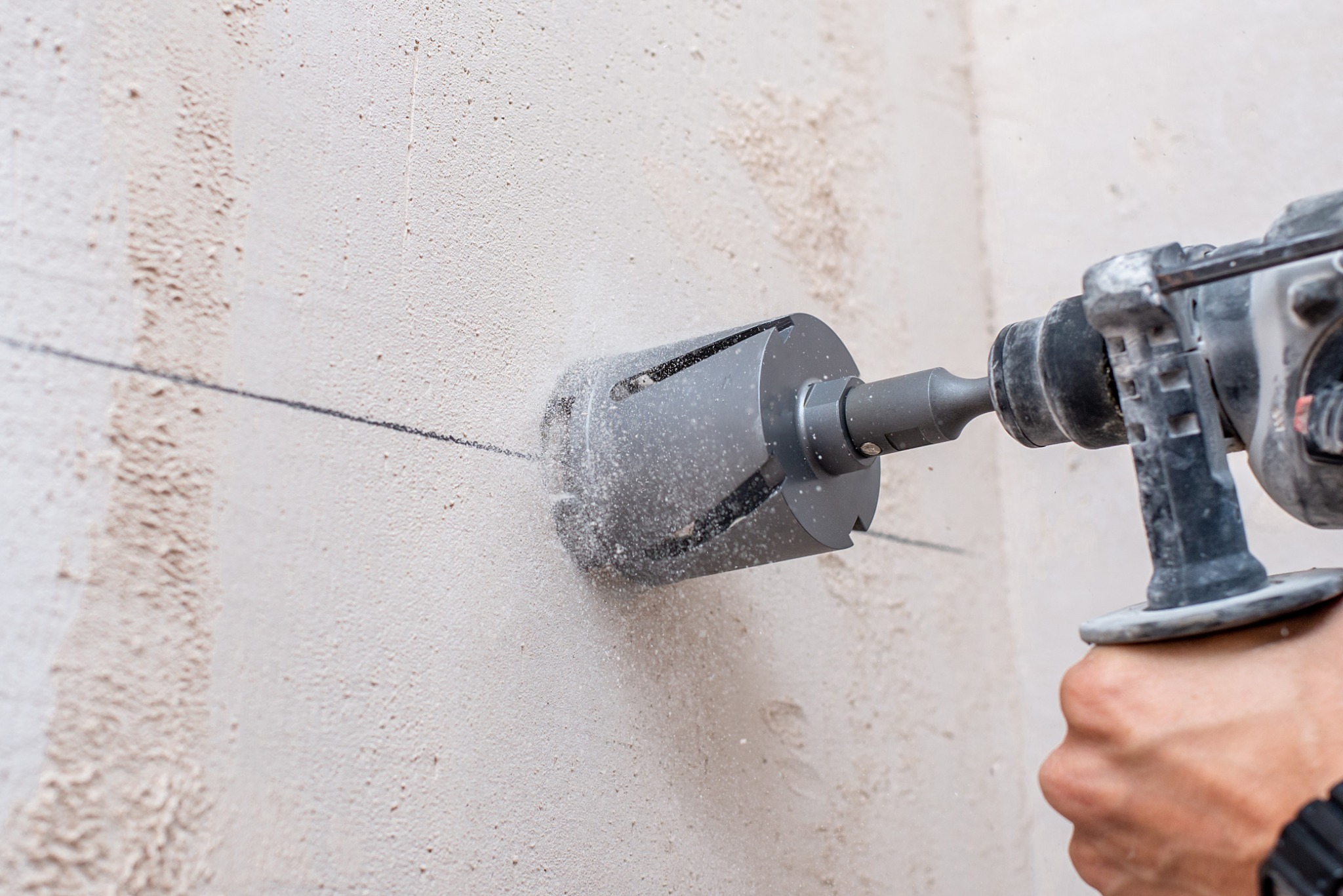 Power drill making a precise opening in a masonry wall for a mounted fixture.