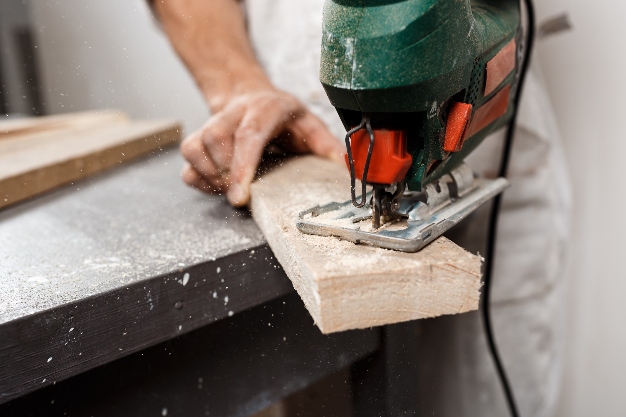 Close-up of a jigsaw cutting a solid piece of wood in a workshop.